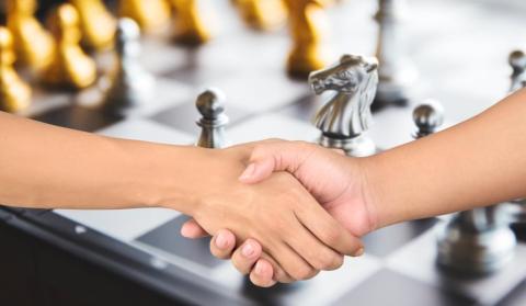 Shaking hands in front of a chess board