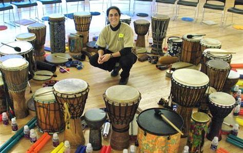 Circle of hand drums with a woman seated in the center.