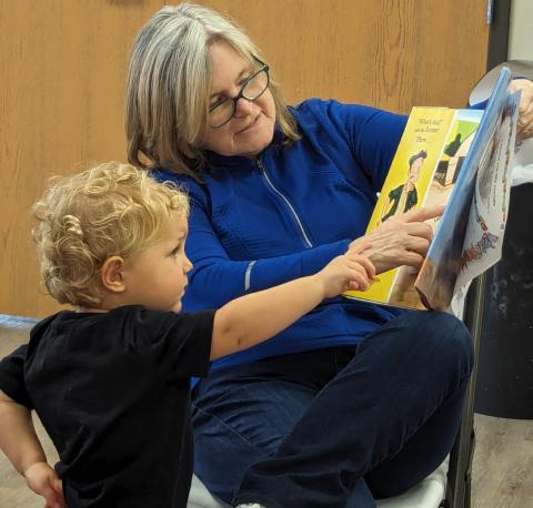 child and elder lady reading a book together