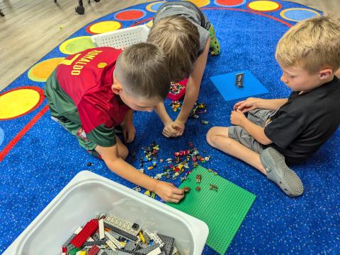 Children sitting on a mat building legos together