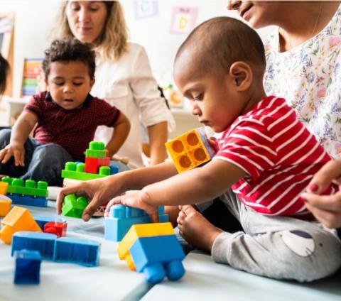 Babies with caregivers playing with bricks