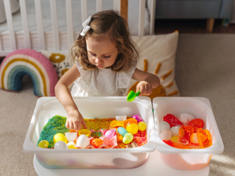 girl playing with tub of rice and toys