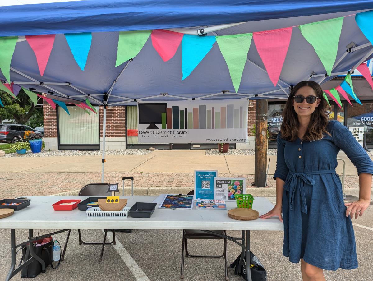 Woman standing beside booth tent decorated with flags