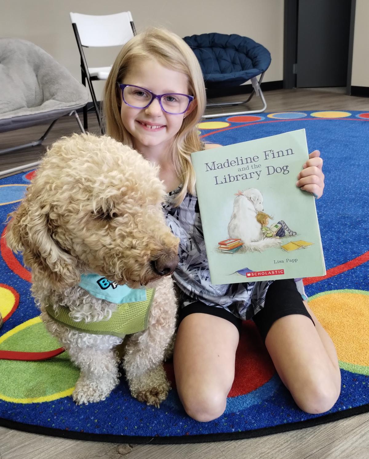 labradoodle dog and girl with book