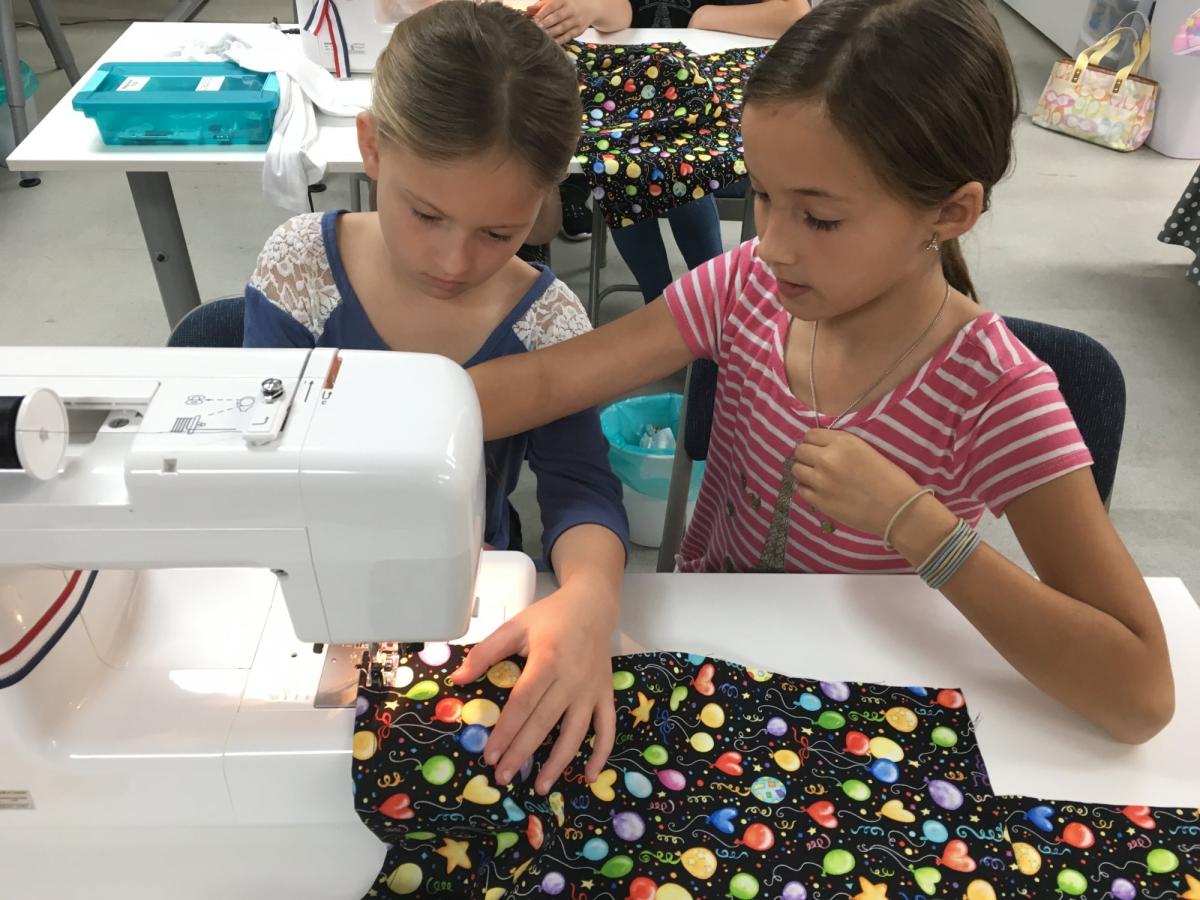 2 children using a sewing machine